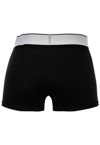 Boxers en coton noir avec une ceinture élastique blanche. Présente une texture lisse et une coupe classique avec des ouvertures pour les jambes.