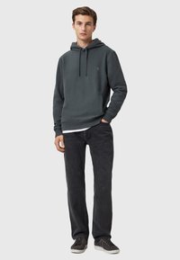 Felpa grigia con cappuccio e lacci, strato interno bianco, abbinata a jeans grigi scuri e scarpe da ginnastica grigie. Design semplice con una vestibilità accessibile.