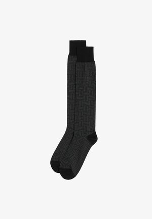 Knee-high socks in a black pattern with white stitching. Textured material and solid black cuffs. Rounded toes and reinforced heels.