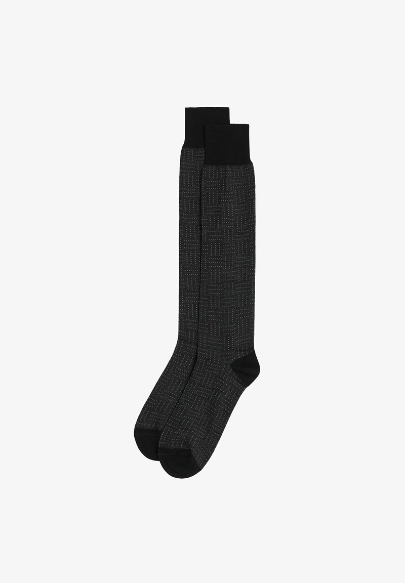Chaussettes jusqu'aux genoux avec un motif noir et des coutures blanches. Matériau texturé et revers noirs unis. orteils arrondis et talons renforcés.