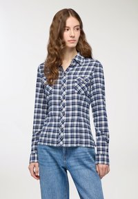 Camicia a quadri navy e bianca con maniche lunghe, design con bottoni sul davanti, due taschini sul petto e una vestibilità leggermente sagomata. Tessuto di cotone testurizzato.