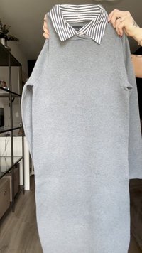 Felpa grigia chiara con una camicia a righe sotto. Materiale morbido, vestibilità comoda, maniche lunghe e scollatura rotonda.