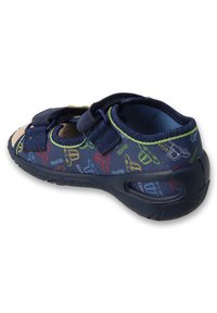 Granatowe sandały z dwiema rzepami, teksturowaną podeszwą i kolorowymi grafikami przedstawiającymi zabawne elementy. Widać korkową wkładkę na palcach.