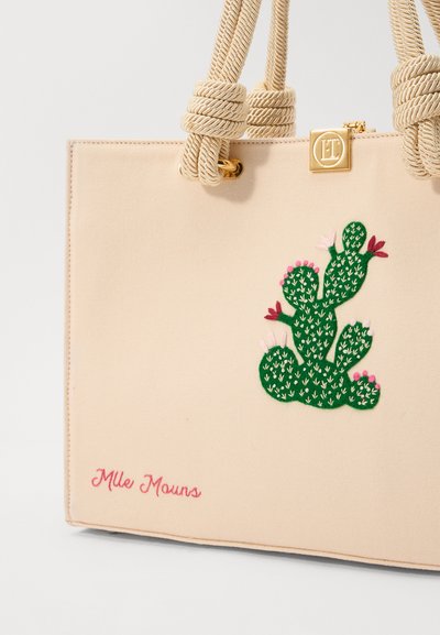 Beige canvas tote bag with twisted rope handles, featuring a green embroidered cactus design and pink floral accents. Text reads "Mlle Mouns."