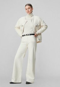 Chaqueta de mezclilla de color claro y pantalones a juego, con un suéter de cuello alto color crema. Cinturón negro con hebilla dorada. Textura suave, forma de pierna ancha.