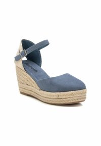 Zapato de cuña de gamuza azul con suela de yute. Cuenta con una correa en el tobillo y un diseño de puntera redonda. La suela es plana con un patrón texturizado.