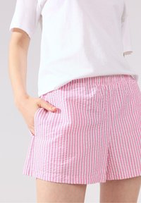 Rosa och vita randiga shorts med resårmidja och sidofickor. Tillverkade av lätt bomull för komfort och andningsförmåga.