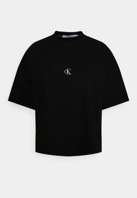 Svart avskuren T-shirt med rund halsringning, oversized korta ärmar och en liten vit broderad logotyp på bröstet. Material i bomullsblandning.