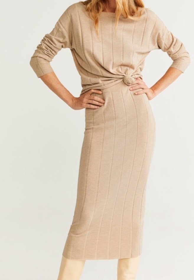 Robe tricotée beige à côtes avec un col rond, des manches longues, un détail de taille froncée et une silhouette midi ajustée. Texture lisse sur l'ensemble.
