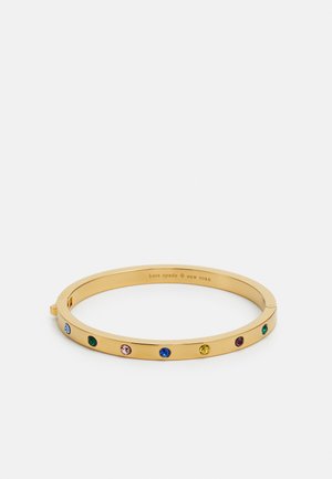 Gold bangle bracelet featuring multiple colored gemstones set along the front, with a smooth, polished finish and a secure clasp.