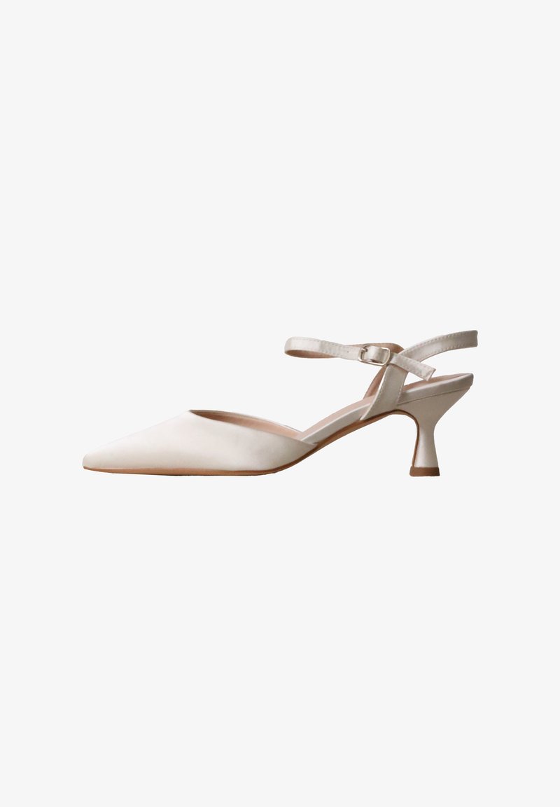 Chaussure slingback en cuir beige à bout pointu avec un talon bas courbé et une bride de cheville réglable avec boucle.