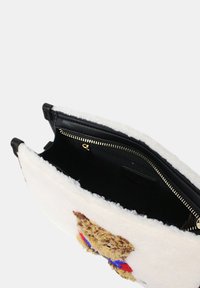 Borsa a mano nera in pelle con superficie esterna in morbido pile bianco, caratterizzata da un design testurizzato a forma di orsetto. Chiusura con zip dorata e interno nero.