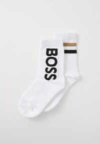 Calcetines blancos de algodón con el texto "BOSS" en negro y un patrón de rayas contrastantes en negro y dorado en uno de los calcetines.