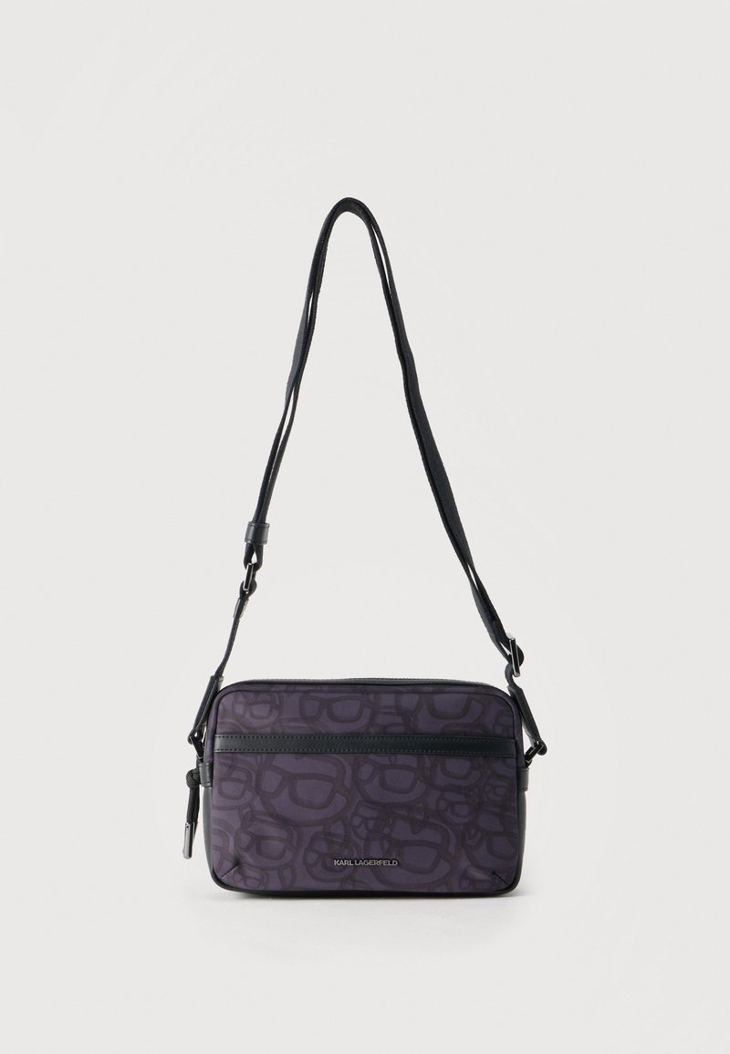 Μικρή ορθογώνια τσάντα ώμου σε σκούρο μωβ χρώμα με αφηρημένο σχέδιο, εμπρός τσέπη με φερμουάρ, ρυθμιζόμενο μαύρο λουράκι και ασημένιο λογότυπο "Karl Lagerfeld".