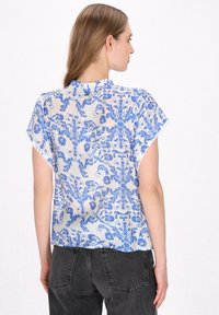 Kortærmet bluse i blå og hvid blomsterprint med rynket halsudskæring; gennemsigtigt, let stof; lige snit, subtil blondekant.