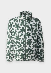 Veste en polaire avec un col montant, présentant un motif abstrait vert et blanc, fermeture éclair et surface texturée.