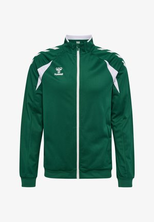 Grøn sportjakke med fuld lynlås og hvide chevron-accenter på skuldrene og hvide sidepaneler, med et lille hvidt "hummel"-logo på brystet.