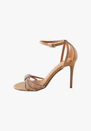 Nude leren stiletto-hak schoen, met een geknoopte voorkant en strasaccenten, en een dunne enkelband met een vierkante gesp.