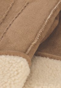 Bruin suède stof met een fleece voering, met een gestructureerd oppervlak en contrasterende stiknaden. Zacht, warm en ontworpen voor comfort.