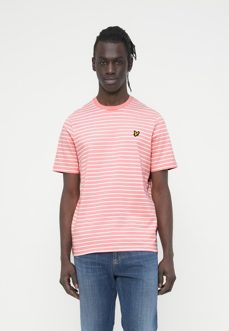 Ροζ ριγέ μπλουζάκι με στρογγυλή λαιμόκοψη και κοντά μανίκια, με ένα μικρό κίτρινο λογότυπο πεταλούδας στο αριστερό στήθος. Υλικό από βαμβάκι.