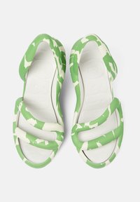 Vihreä-valkoinen camouflage-kuvioinen sandaalit, joissa on pehmeä kumimateriaali, leveät hihnat ja teksturoitu valkoinen pohja.