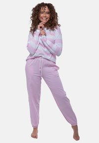 Maglia a maniche lunghe a righe rosa con una grafica di faccina sorridente, abbinata a pantaloni del pigiama rosa uniti. Tessuto leggero, vestibilità ampia, polsini elasticizzati.