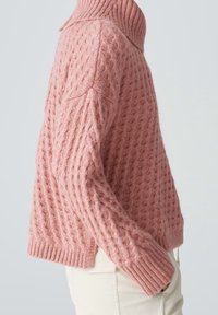 Różowy sweter dziany z wysokim kołnierzem, z teksturowanym wzorem i ściągaczami na rękawach. Krótki, pudełkowy krój z miękkiego materiału.