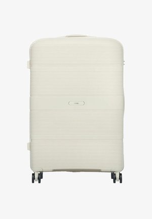 Duża walizka o twardej skorupie w kremowym kolorze z poziomymi żłobieniami, cztery czarne obrotowe kółka i górny uchwyt.