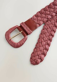 Cinturón tejido en rosa suave, con una correa de cuero marrón y una hebilla de metal en tono dorado. La textura es texturada y trenzada para mayor flexibilidad.