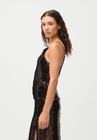 Black and bronze sequin top with thin straps, featuring a fitted design and a slight sheen. Textured sequins cover the entire surface.