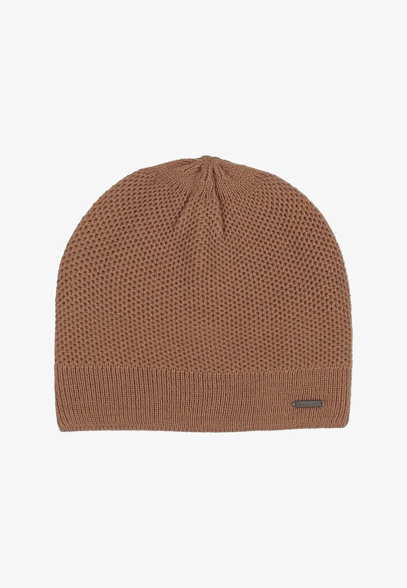 Light brown knitted beanie with a textured pattern and a small rectangular metal brand tag on the ribbed edge.