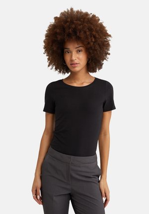 Zwarte korte mouwen t-shirt gemaakt van gladde stof, met een ronde halslijn, gecombineerd met grijze pantalon. Eenvoudig en getailleerd ontwerp.