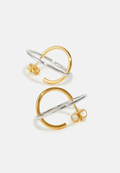 Gold- und Silber-Ohrstecker mit einem kreisförmigen Design. Das Gold hat eine glatte Textur, während das Silber poliert und leicht glänzend ist.