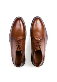 Scarpe in pelle marrone con una finitura liscia, caratterizzate da una punta arrotondata, lacci sottili e una suola in gomma nera a profilo basso.