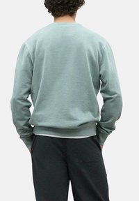 Sudadera verde clara con mangas largas, cuello redondo, puños y dobladillo acanalados. Textura suave, ajuste estándar, diseño minimalista.