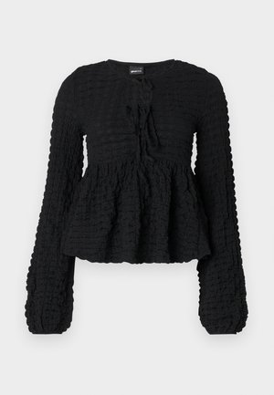 Haut à manches longues noir texturé avec une taille peplum froncée, un col rond et un détail de lien à l'avant. Présente un motif de tissu froissé.