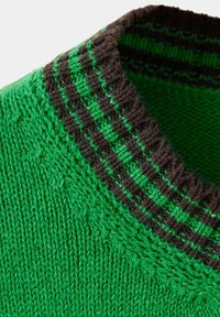 Gros plan d'un pull vert tricoté montrant un col rond avec des côtes rayées noires et vertes.