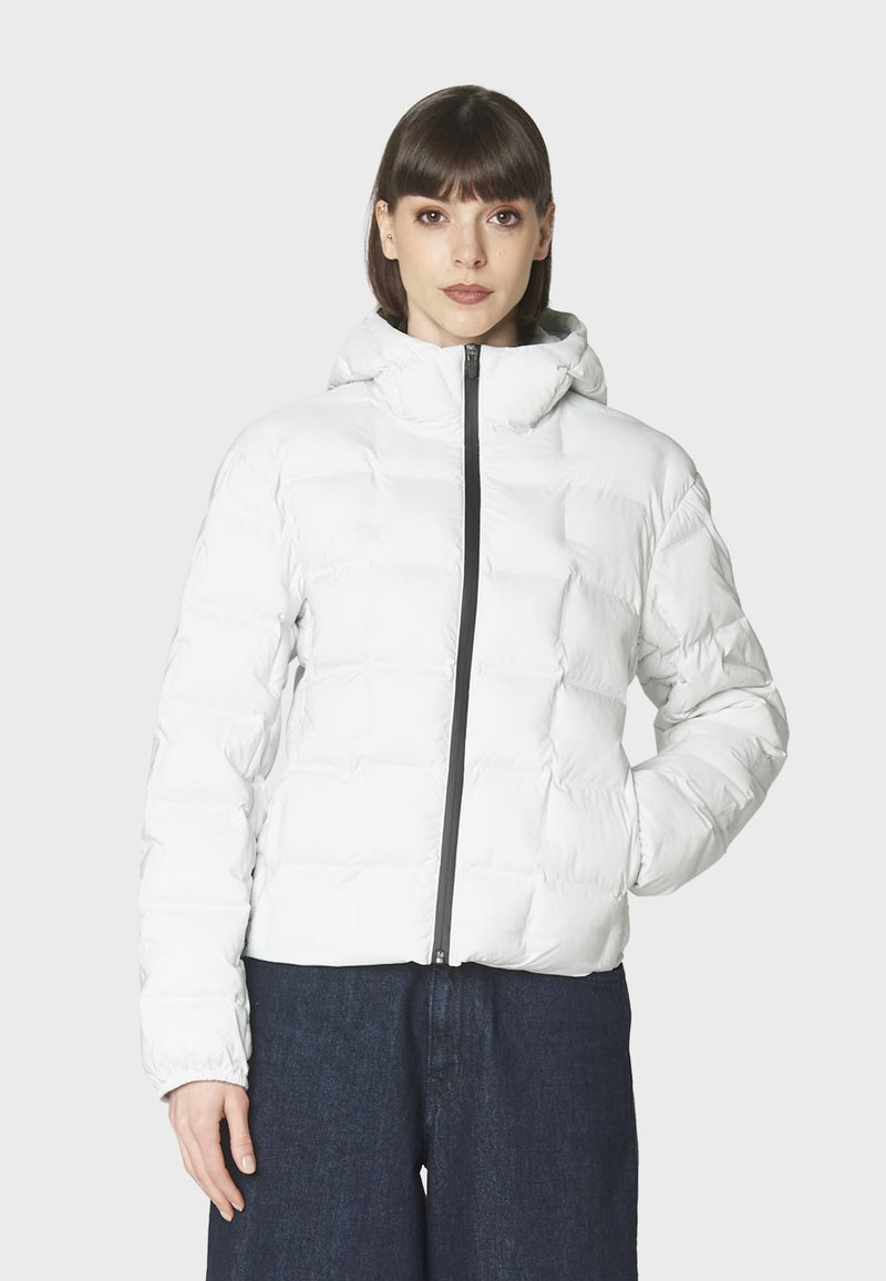 Vit puffjacka med huva, med dragkedja fram och kviltad textur. Bärs över mörka denimbyxor som framhäver en figurnära silhuett.