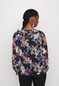 Blusa preta com padrão floral colorido em roxo, laranja e teal; tecido transparente, mangas longas e detalhe de decote em babados.
