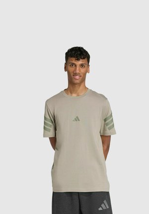 Hellkhakifarbenes Kurzarm-T-Shirt aus weicher Baumwolle, mit drei grünen Streifen an jeder Schulter und einem Adidas-Logo auf der Brust.