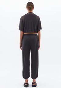 Grijze twee-delige outfit met een kortmouwtop en losse broek. Het materiaal lijkt lichtgewicht met een gladde textuur.