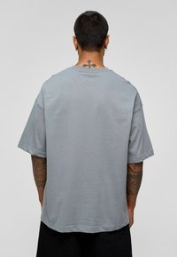 Grijze katoenen T-shirt met korte mouwen, ontspannen pasvorm en een rechte zoom. Heeft een ronde hals en minimale stikdetails.