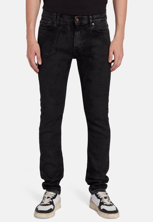 Schwarze Denim-Jeans mit schlanker Passform, die nur minimale Abnutzungserscheinungen aufweisen, im klassischen Fünf-Taschen-Design und mit Kupferbeschlägen. Gereicht mit schwarz-weißen Sneakers.
