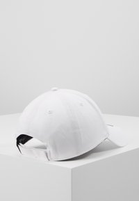 Weißes Baseballcap aus Baumwolle, mit geschwungenem Schirm, sechsseitigem Design und einem verstellbaren Riemen hinten für einen sicheren Sitz.