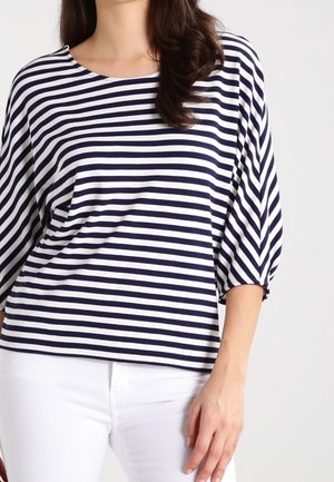 Chemise rayée bleu marine et blanche avec une coupe ample, un col large et des manches trois-quarts, fabriquée en tissu de coton doux.