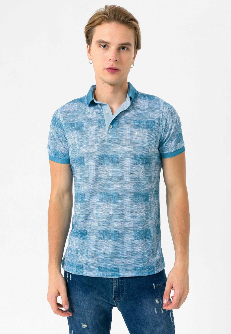 Lyseblå polo t-shirt med korte ærmer, tekstureret mønster og en blød krave. Har blå detaljer og et lille logo på brystet.