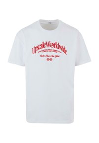 White cotton t-shirt featuring bold red text: "Upscale Worldwide" arching above smaller text, with a star logo and city names below.