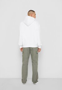 Hvid hætte sweatshirt med en afslappet pasform, parret med olivengrønne cargo pants med sidelommer og lige ben.