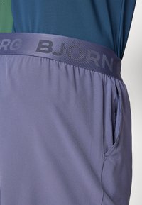 Fialové športové šortky s elastickým pásom a embosovaným logom "BJÖRG", bočnými vreckami a hladkým, ľahkým materiálom.