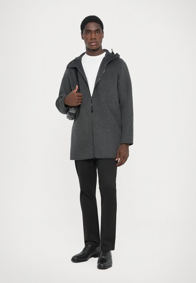 Gray wool blend coat with a hood, zippered front, and spacious pockets. Worn over a white shirt and paired with black trousers and shoes.